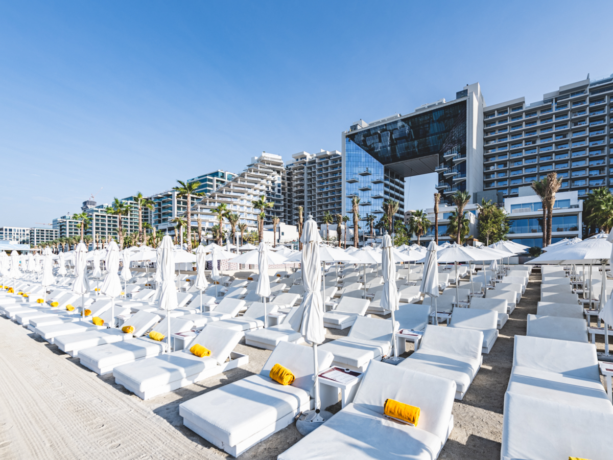 modern beach resort hotel with white chaise lounges and sun umbrellas in the foreground