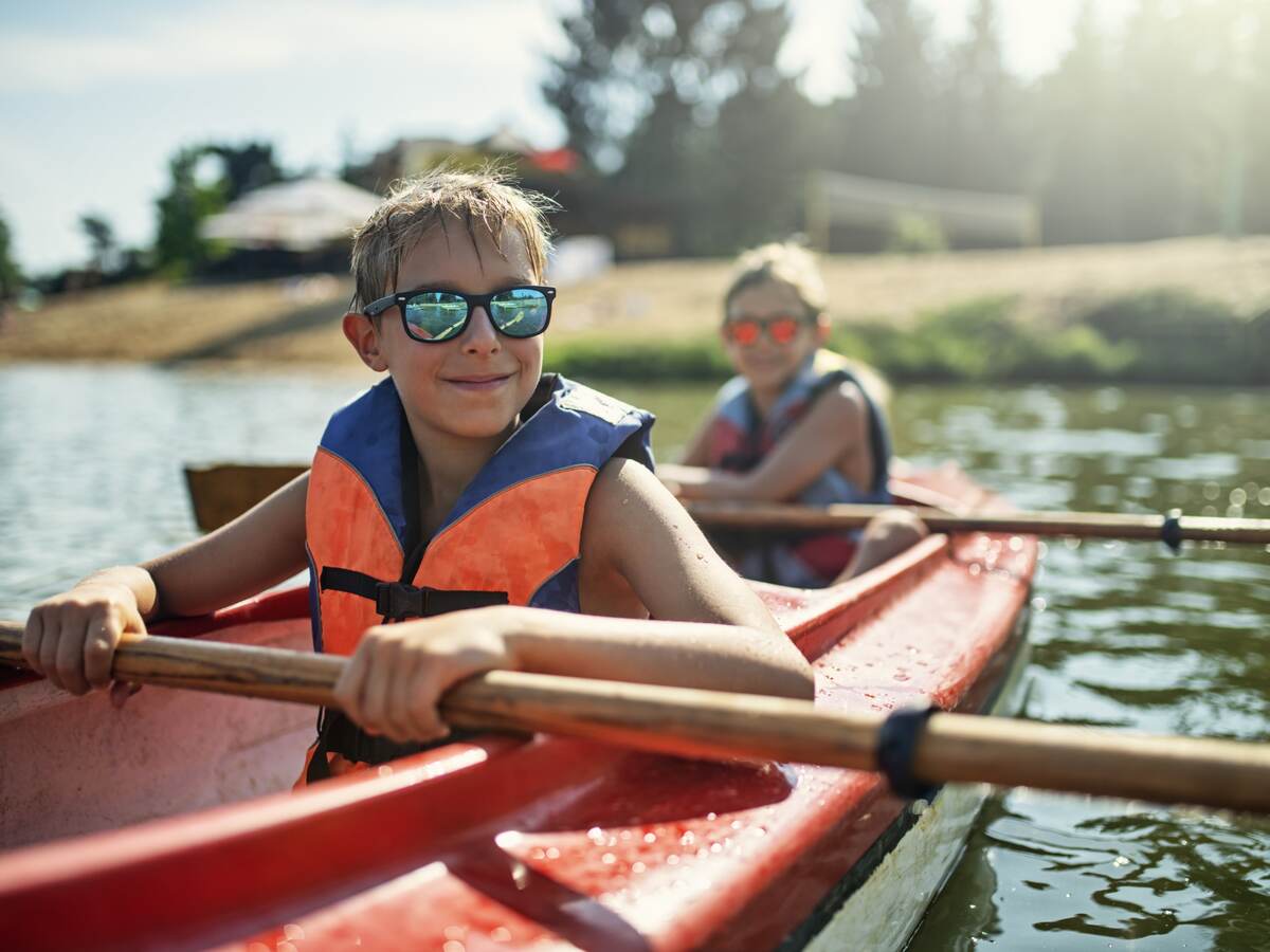 Children in life jackets rowing a canoe.