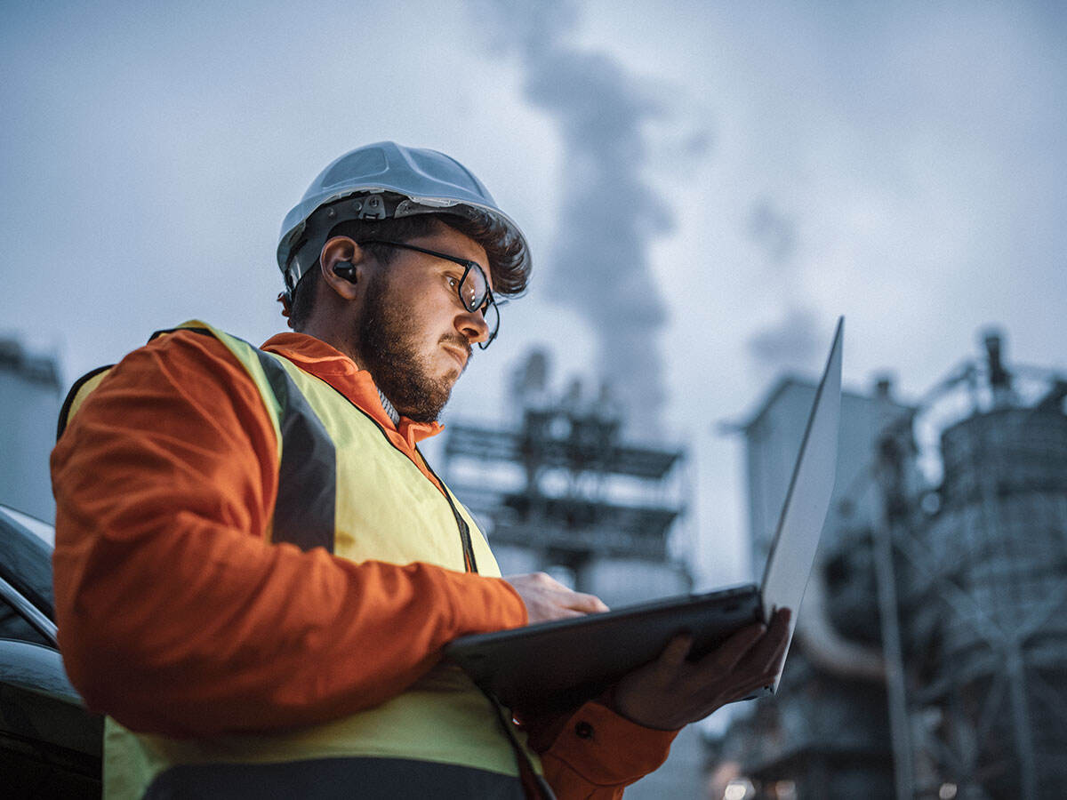 Engineer looking at a laptop outdoors at a plant