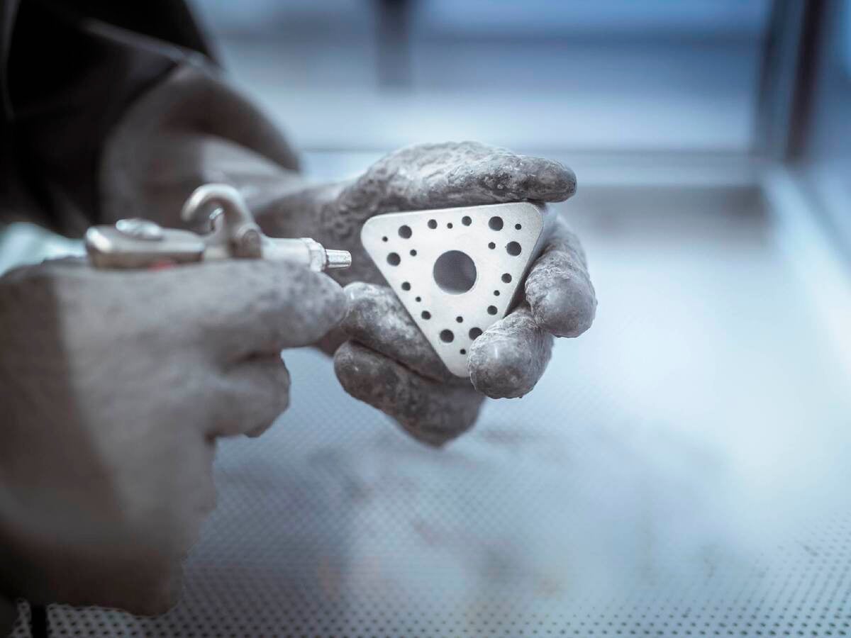 Hands holding metal 3D printed object in laboratory. 