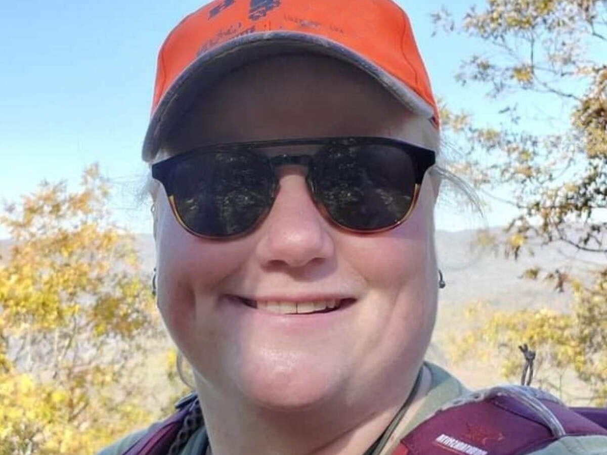 Close-up of Trenda in orange hat and sunglasses while hiking in mountains. 