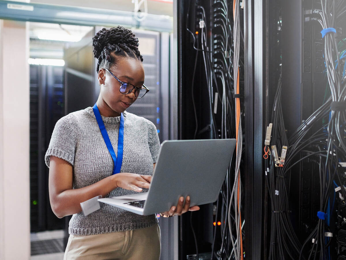 Person working on laptop in server room 