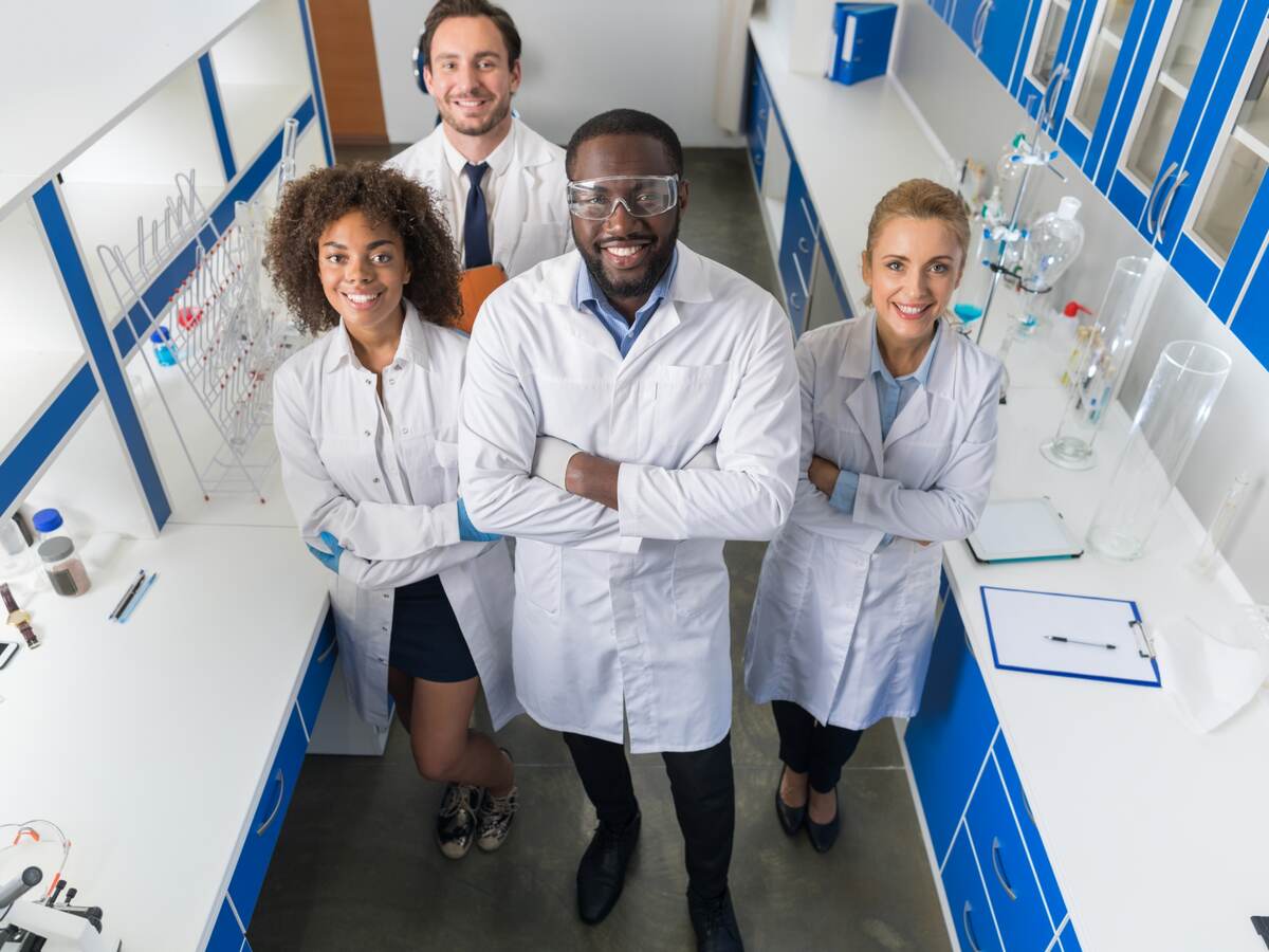 African American Scientist With Group Of Researchers In Modern Laboratory Happy Smiling, Mix Race Team Of Scientific Researchers In Lab.