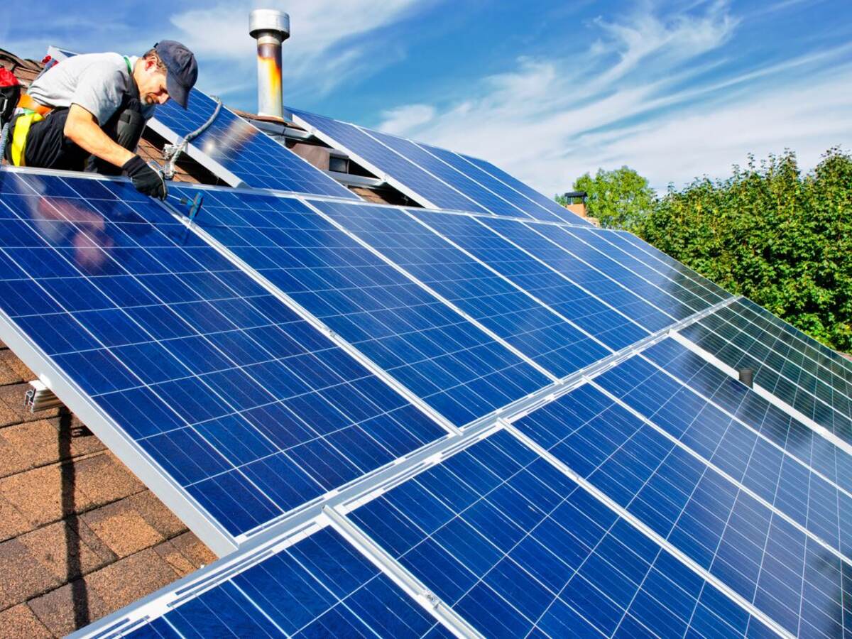 Construction worker on the roof of a house installing solar panels