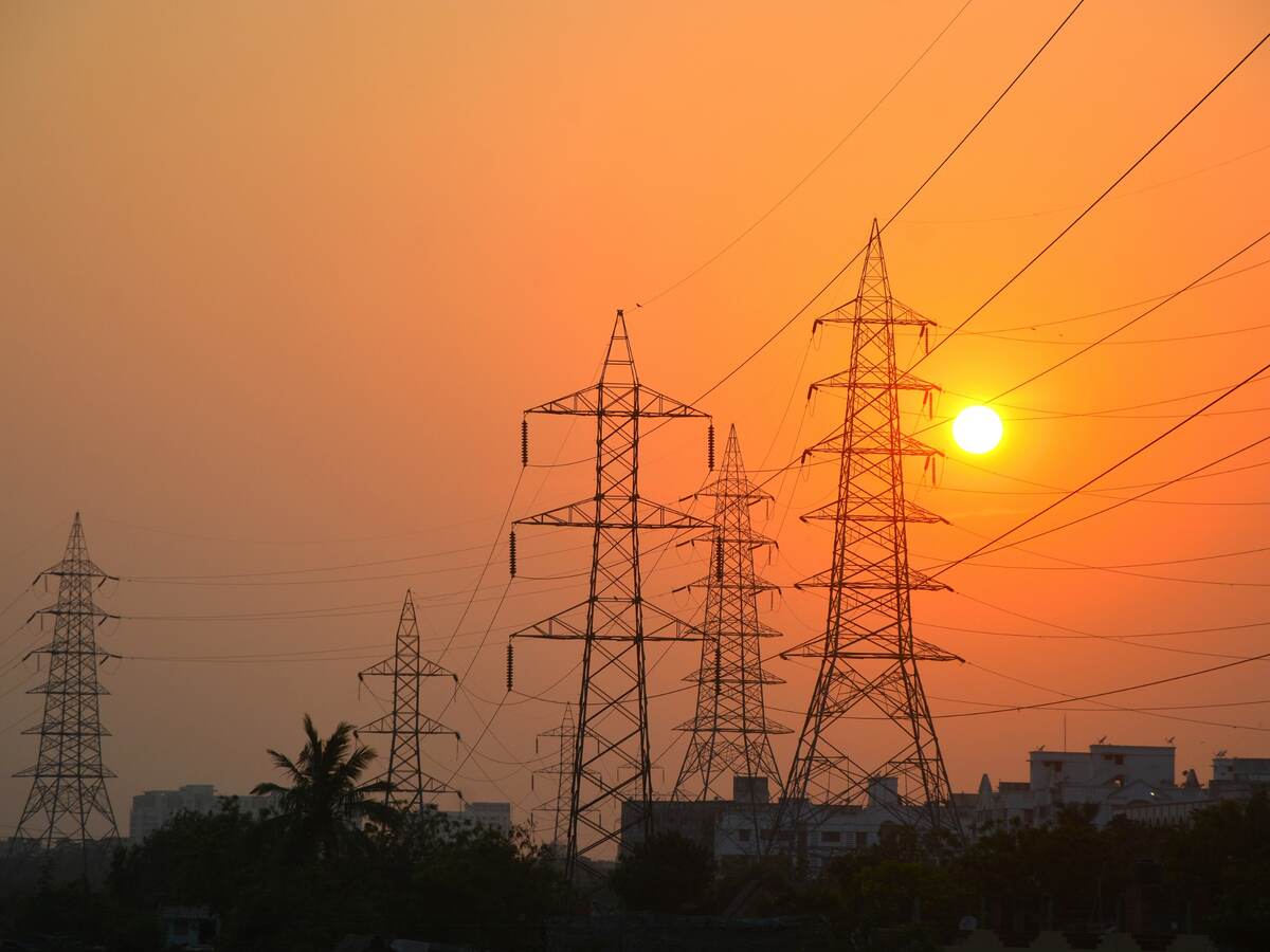 Sunset behind electrical power lines and buildings.