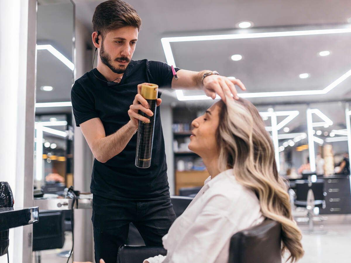 Hair stylist spraying hairspray on customer