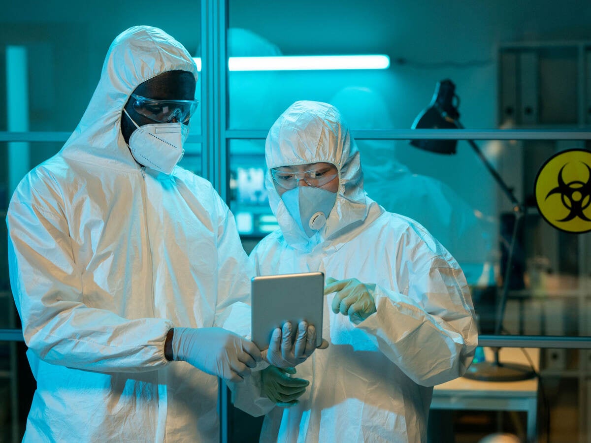 Two workers in a scientific laboratory discussing online clinical data