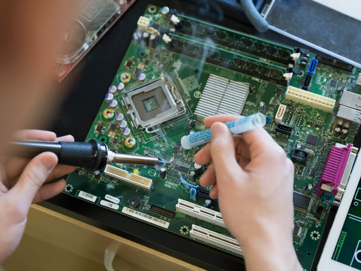 A person using a screwdriver and working on a computer board