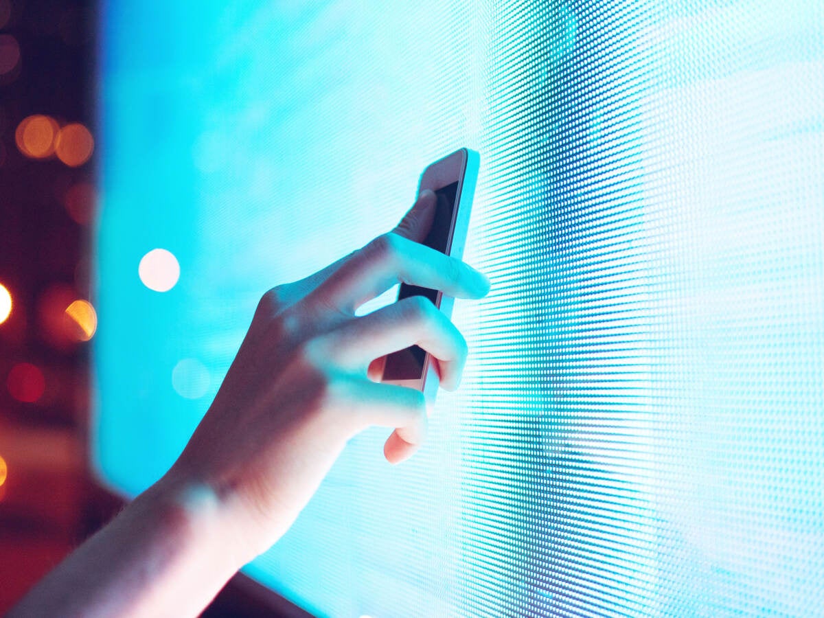 Person holding a smart phone up to a screen