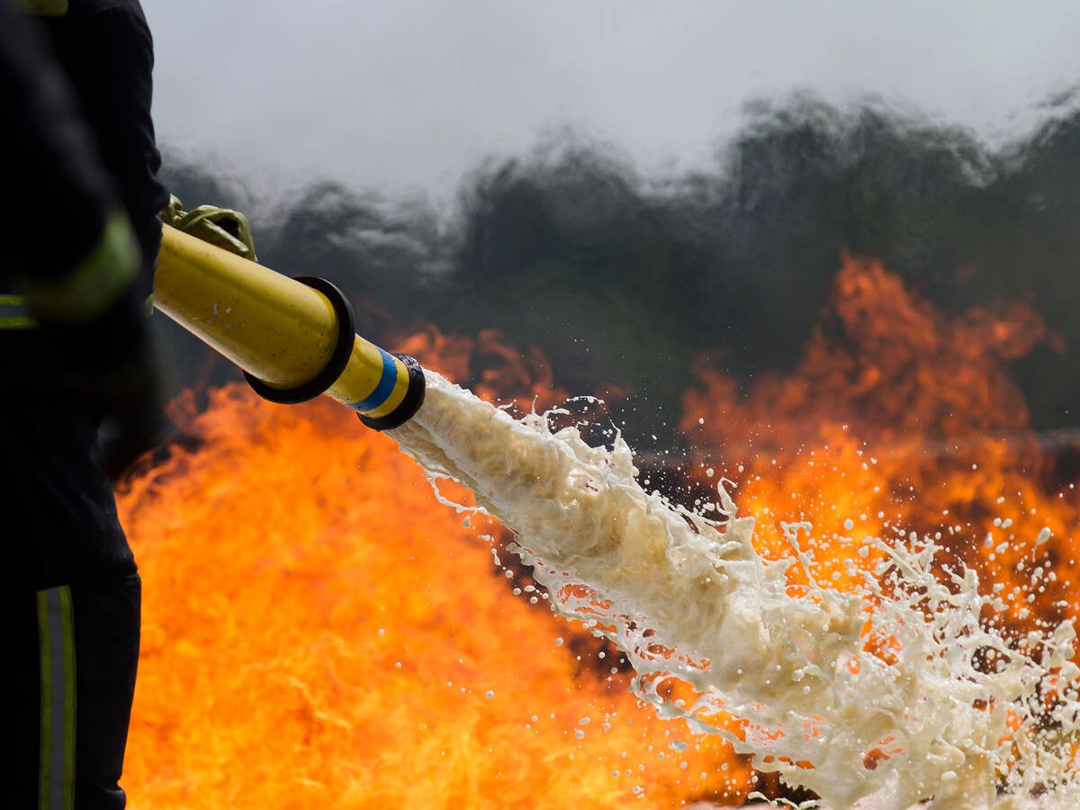 Firefighter using foam to put out a fire