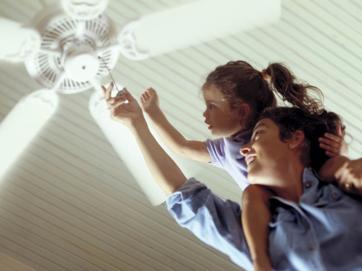 Mother and daughter turning on a ceiling fan.