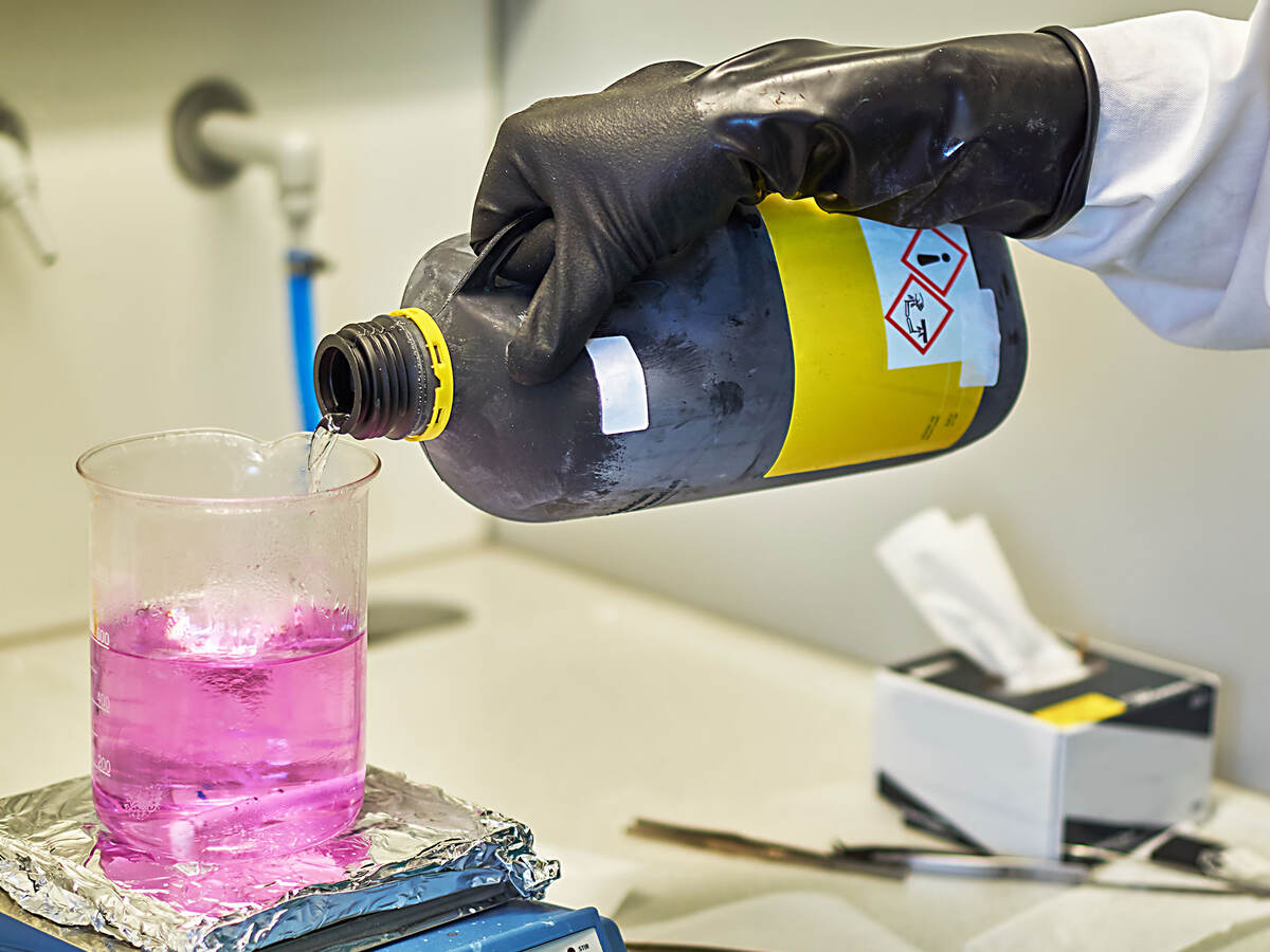 a lab tech pouring hazardous chemical into a beaker