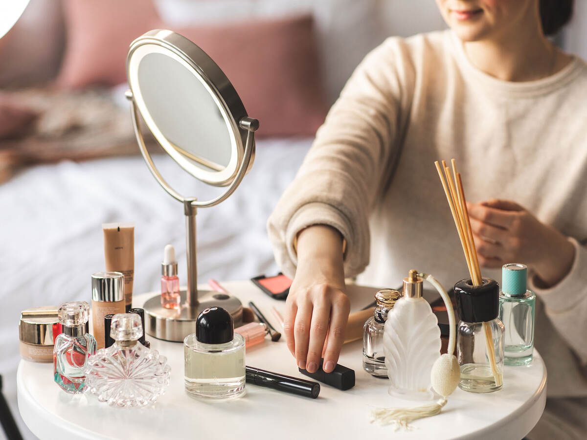 reaching out to pick up a lipstick from a table full of beauty products
