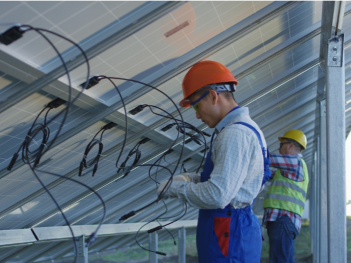 Two solar panel installers twisting wire 