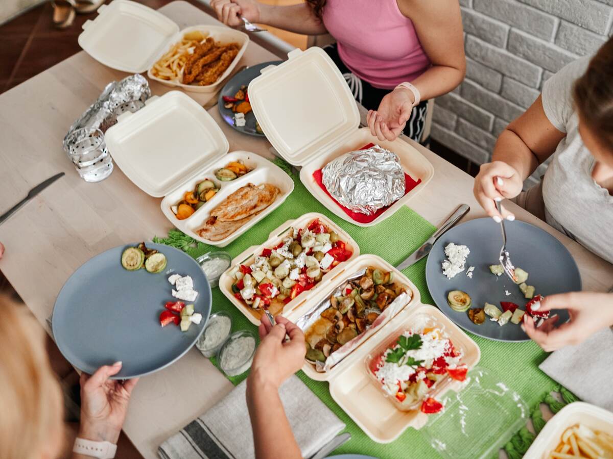 Family eating takeaway meals at home.