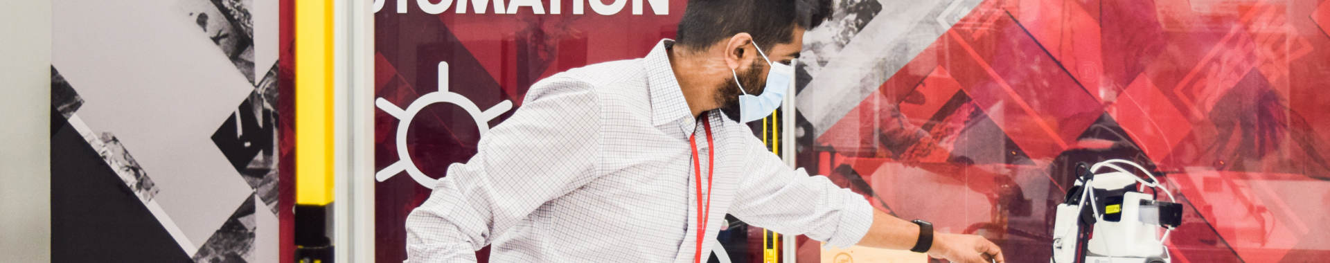 An engineer wearing a mask inspects an industrial automation piece of equipment