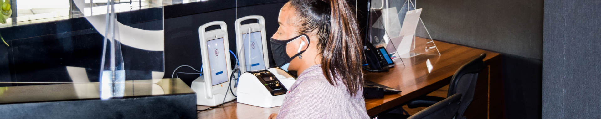A woman wearing a mask greets a visitor wearing a mask at the UL front desk