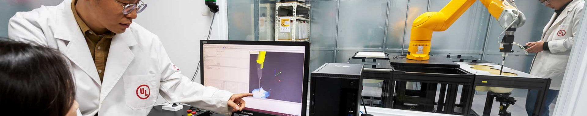UL laboratory technicians inside lab with computer and robotic arm
