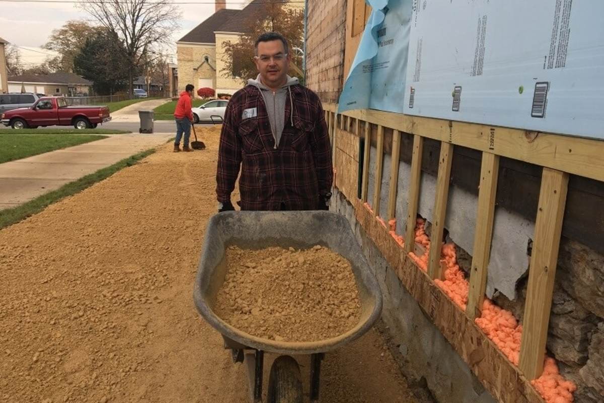 UL volunteers moves gravel in a wheelbarrow