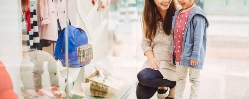 A mother and her daughter look at a clothing store window display in China.