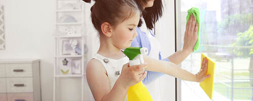 Girl helping her mother clean windows