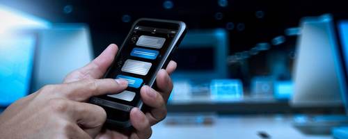 A hand holds a smartphone while the other hand converses with a chatbot.