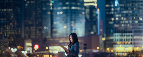 Woman looking at her tablet at night in the city