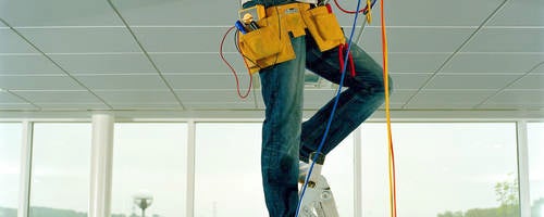 Man on step ladder, working through gap in ceiling, low section