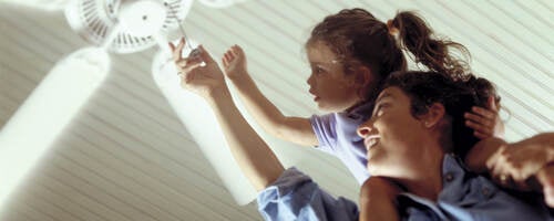 Mother and daughter turning on a ceiling fan.