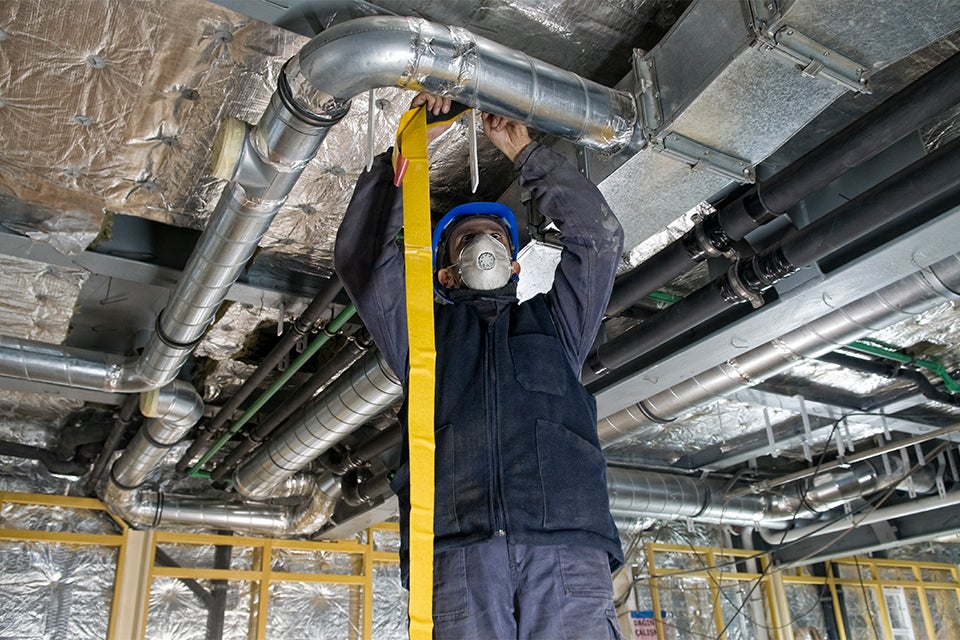 Technician in a mask working on an HVAC system
