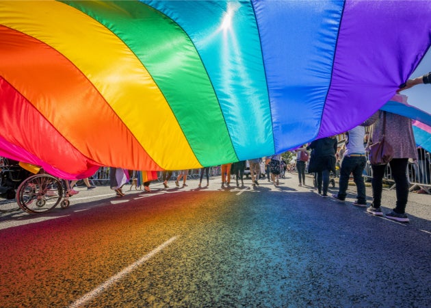 A rainbow flag carried by a diverse group of people during a PRIDE parade celebration