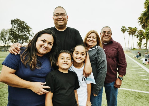 A multigenerational family smiles together on a soccer field