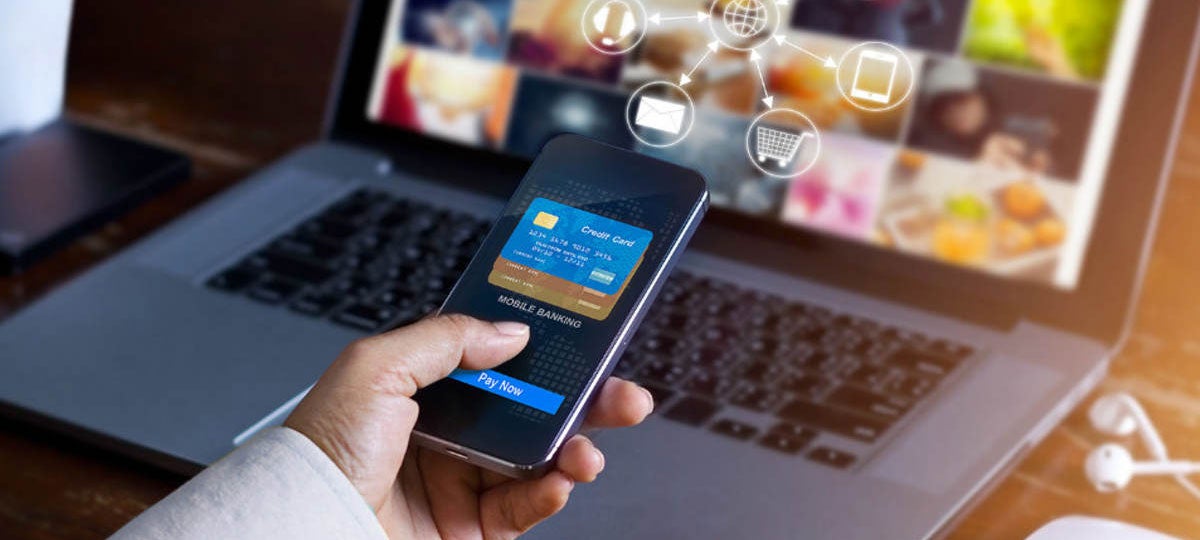 Using mobile banking app while online shopping with a laptop